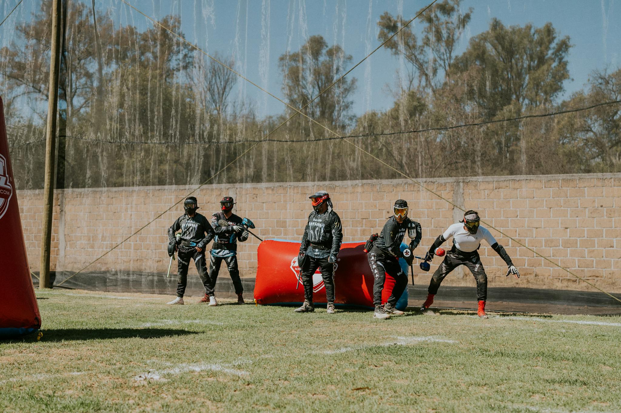 Paintball players in gear at the start of a thrilling game on an outdoor field.